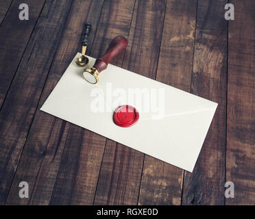 Old letter envelope with red wax seal and stamp on wooden background. Stock Photo