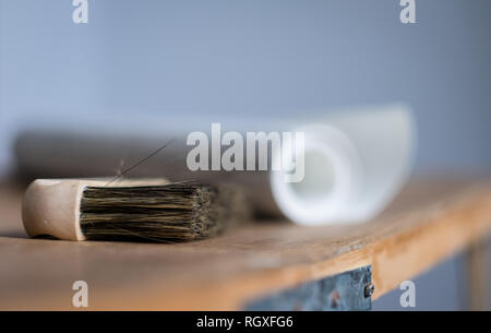 Wallpaper brush and a roll of wallpaper on a pasting table ready to decorate a room Stock Photo