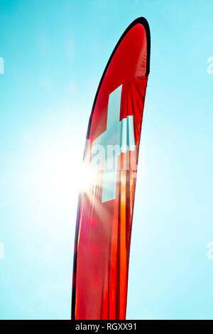 Swiss Banner Flag with Sunbeam and Against Blue Sky. Stock Photo