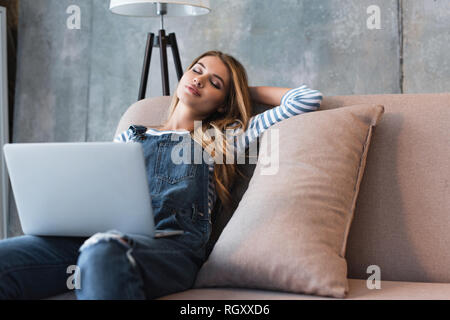 adult beautiful woman dreaming on sofa with laptop