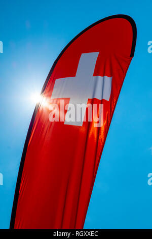 Swiss Banner Flag with Sunlight and Against Blue Sky in Switzerland. Stock Photo