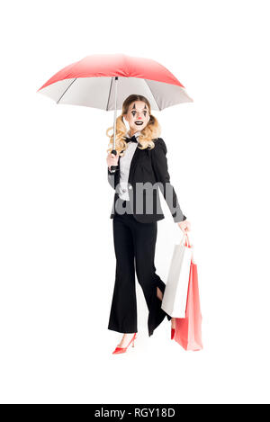 smiling female clown holding shopping bags and umbrella isolated on white Stock Photo