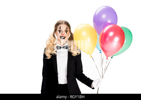 cheerful female clown in suit holding balloons and smiling isolated on white Stock Photo