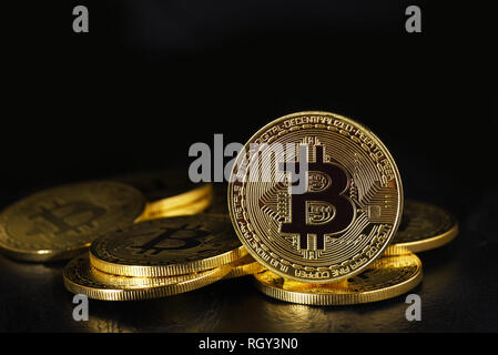 Bitcoin: A pile of physical bit coins, aslo called Digital Currency or Cryptocurrency, with one standing on edge on black with reflection and copy spa Stock Photo