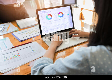 Rearview young woman working with laptop in office, sitting at desk Stock Photo
