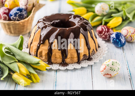 Delicious holiday slovak and czech cake babovka with chocolate glaze. Easter decorations - spring tulips and eggs. Stock Photo
