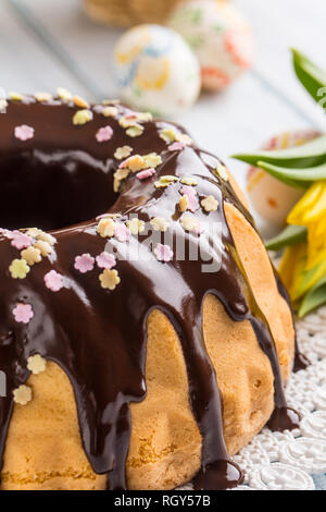 Delicious holiday slovak and czech cake babovka with chocolate glaze. Easter decorations - spring tulips and eggs. Stock Photo