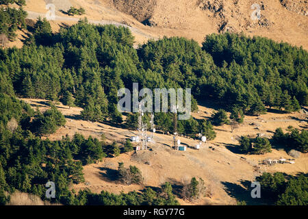 Telecommunications Cell Phone Towers With Antennas On Background Of Mountains Forest. Aerial View Stock Photo