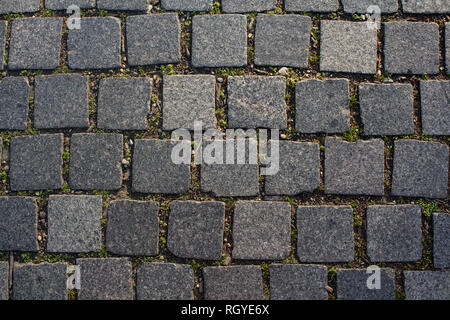 A squared granite walkway with moss and grass between the stones for a patterned background. Stock Photo