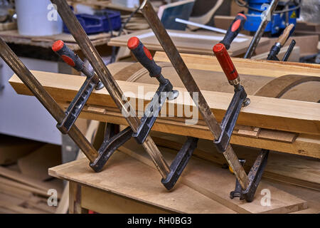 Production of curved MDF cabinet doors. Metal clamps tightening mdf details. Wooden furniture manufacturing process Stock Photo