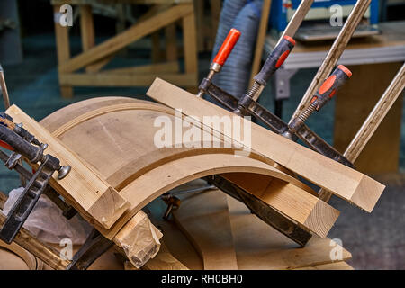 Production of curved MDF cabinet doors. Metal clamps tightening mdf details. Wooden furniture manufacturing process Stock Photo