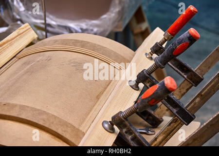 Production of curved MDF cabinet doors. Metal clamps tightening mdf details. Wooden furniture manufacturing process Stock Photo