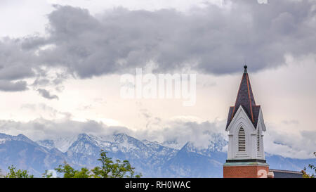 Church steeple against mountain and cloudy sky Stock Photo