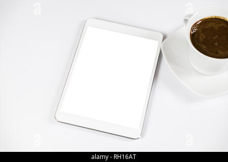 Computer tablet with white empty screen next to coffee. The tablet is on the white table. View from the top. Close-up. Stock Photo