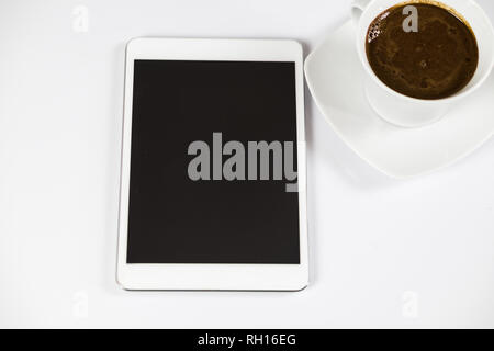 Computer tablet with black empty screen next to coffee. The tablet is on the white table. View from the top. Close-up. Stock Photo