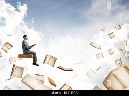 Man reading book and many of them flying in air Stock Photo