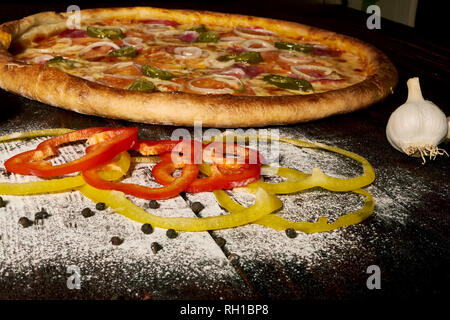 Pepperoni pizza with ham and jalapeno chili peppers on old wooden table Stock Photo