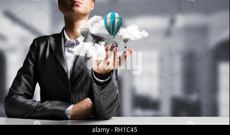 Woman presenting flying balloon in hand. Stock Photo