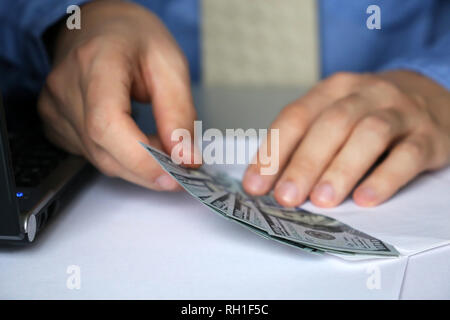 Man in business clothes pulls money out of the envelope. US dollars in male hands close-up, concept of cash, office, income, bribe, loan, salary Stock Photo