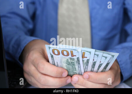 Man holding US dollars in hands, close-up. Clerk, official, manager or businessman counts the money sitting in office, concept of a salary, bribe Stock Photo