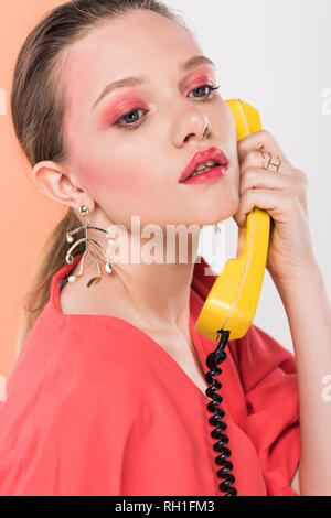 beautiful fashionable girl talking on retro telephone with living coral on background Stock Photo