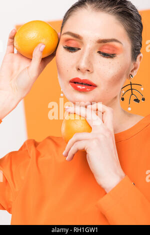 beautiful stylish woman holding oranges and posing with turmeric on background Stock Photo