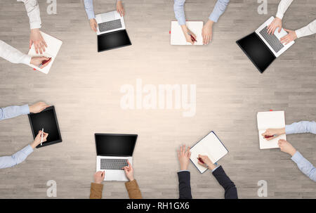 Group of people with devices in hands having desk discussion and making reports together on laptop, tablet, notebook  Stock Photo
