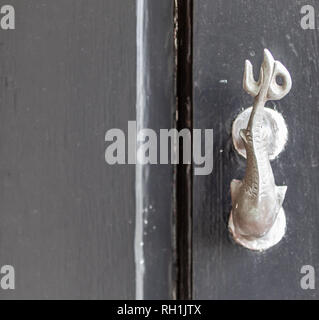 Brass door knocker in the shape of a fish mounted on a black door Stock Photo