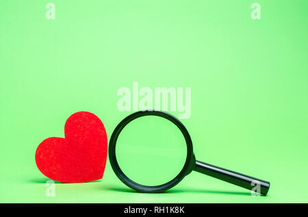 Red heart and magnifying glass. Concept of love and relationships. Search for love. Valentine's Day. Loneliness. Find a donor for blood transfusions.  Stock Photo