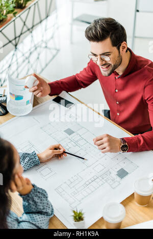 couple of architects sitting at table and working on blueprints in office Stock Photo
