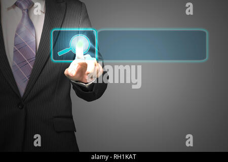 Businessman pushing on future touch screen with magnifier icon in space for searching in dark background Stock Photo