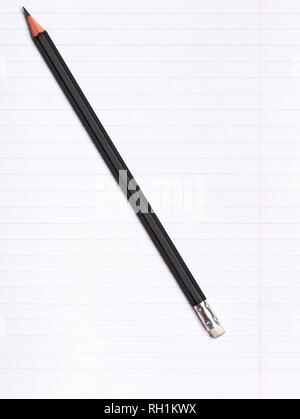 On a sheet of paper notebook with lines lies a black graphite pencil. Copy space. Education concept Stock Photo