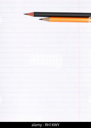 On a sheet of paper notebook with lines are black and yellow graphite pencils. Copy space. The concept of education. Flat surface Stock Photo