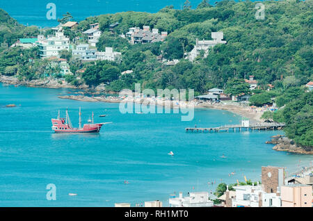 Bombinhas - SC, Brazil - December 18, 2018: Tourists onboard of the pirate ship called Dragao Vermelho (red dragon) docking at Trapiche and the Praia  Stock Photo