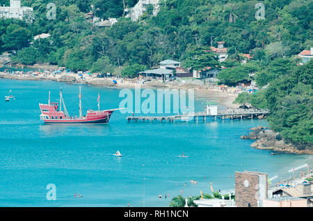 Bombinhas - SC, Brazil - December 18, 2018: Tourists onboard of the pirate ship called Dragao Vermelho (red dragon) docking at Trapiche and the Praia  Stock Photo