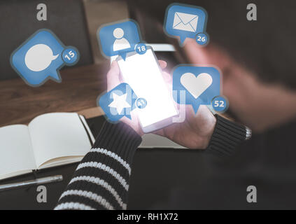 man using smartphone with social media notification icons hovering above glowing screen Stock Photo