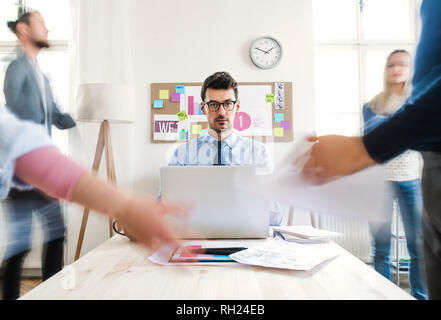 Group of young businesspeople around table in a modern office, having meeting. Motion blur. Stock Photo
