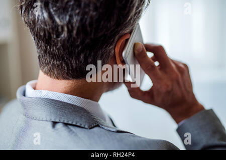 A rear view of mature businessman with smartphone making a phone call. Stock Photo