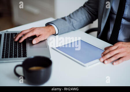 A midsection of businessman sitting at the table, using tablet. Copy space. Stock Photo