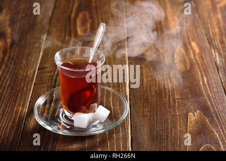 Hot Turkish tea in glass with steam on wooden background Stock Photo