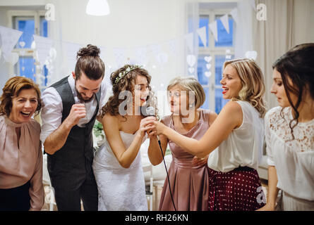 A young cheerful bride with other guests dancing and singing on a wedding reception. Stock Photo