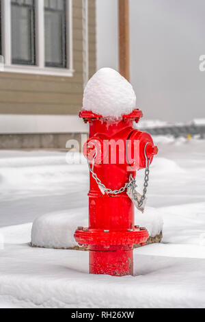 Red fire hydrant on ground with a blanket of snow Stock Photo