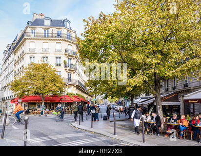 Typical scene on the ile Saint-Louis with people talking, strolling, biking or having a drink at the terrace of a cafe by a sunny autumn morning. Stock Photo