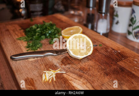 Lemon cut in half with knife on wooden chopping board Stock Photo
