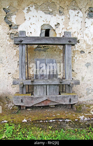 Old Antique wooden wine press in front of the rusty wall Stock Photo