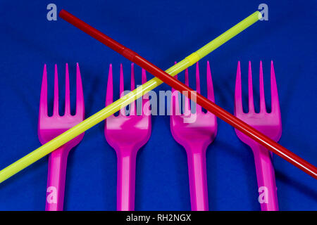 Pink cutlery plastic forks and straws arranged on blue background. Plastic waste problem concept Stock Photo