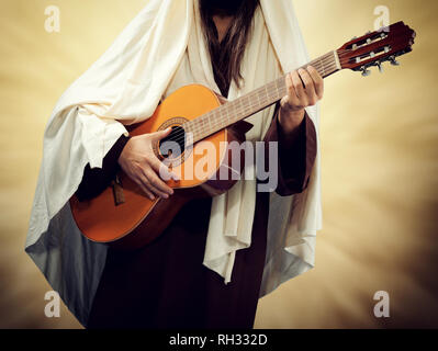 Man wearing Jesus Christ costume and plays guitar. Religious music concept. Stock Photo