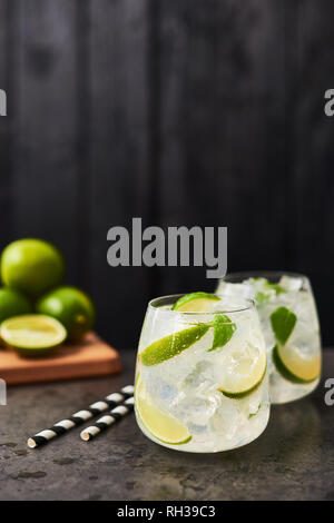 Lemonade or mojito with lime, mint and ice on dark concrete table over black wooden background. Summer drink. Copy space for text. Selective focus. Stock Photo