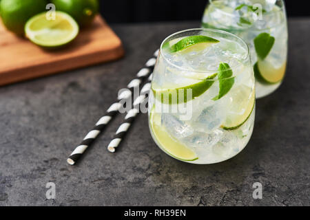 Lemonade or mojito with lime, mint and ice on dark concrete table. Summer drink. Copy space for text. Selective focus. Stock Photo