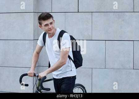 Young hipster style man posing with bicycle on the street sport style picture handsome guy with black backpack ready for trip Stock Photo